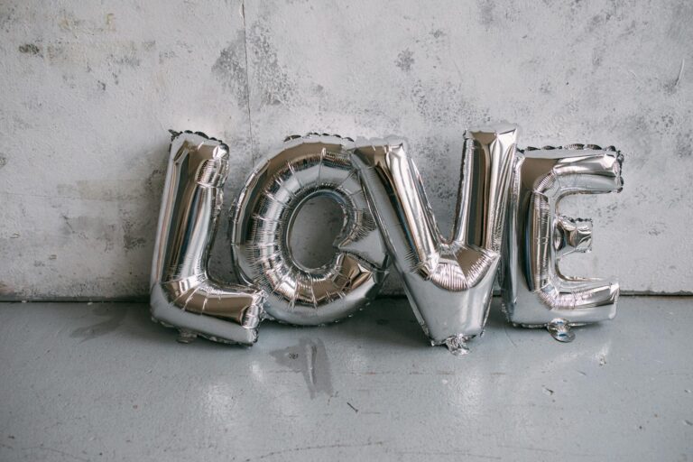 Silver letter balloons spelling 'LOVE' against a textured wall, perfect for celebrations.